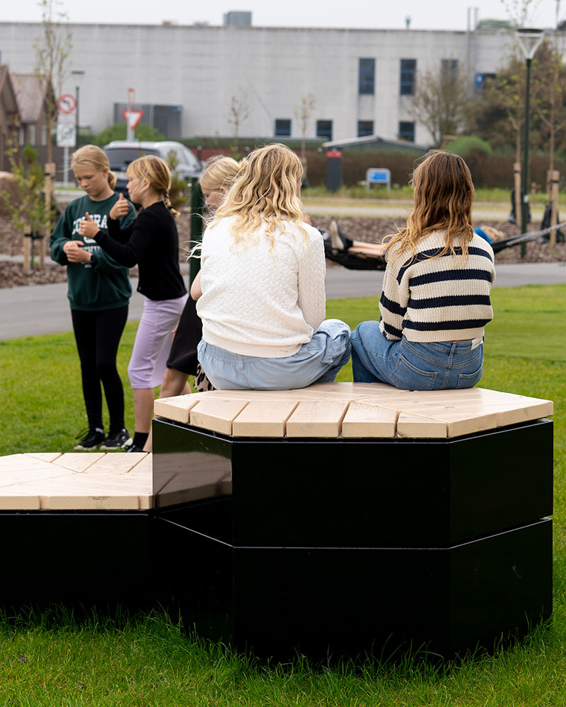 Schulkinder entspannen sich auf einer Sitzkombination von Rosenlund Outdoor-Möbeln vor ihrer Schule.